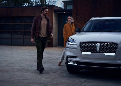 A man and a woman approaching a 2024 Lincoln Aviator® SUV, which illuminates certain lights when they are close | Joe Cooper Lincoln of Edmond in Oklahoma City OK